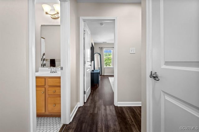 hall with a sink, baseboards, and dark wood finished floors