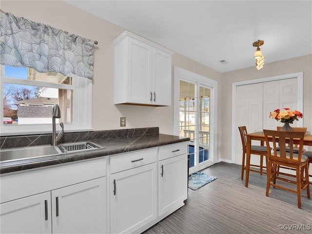 239 Marine Dr, Dunnsville, VA 22454 - kitchen with a sink, dark countertops, white cabinetry, and wood finished floors