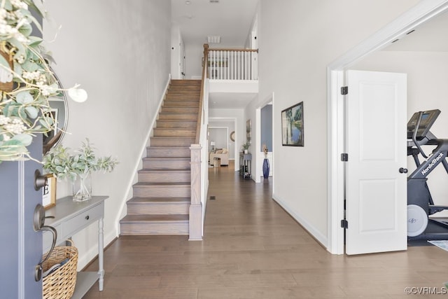 entryway featuring a high ceiling, baseboards, wood finished floors, and stairway