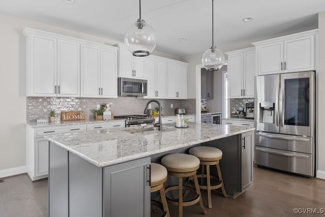 kitchen with a sink, appliances with stainless steel finishes, decorative backsplash, and dark wood-type flooring