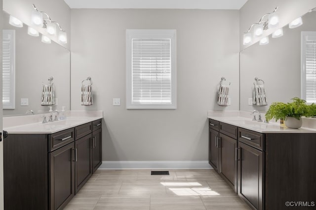 bathroom featuring a sink, baseboards, visible vents, and two vanities