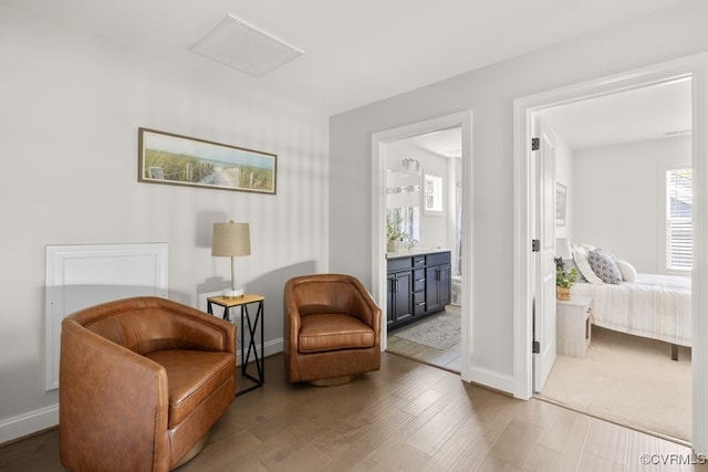 sitting room with baseboards, wood finished floors, and visible vents