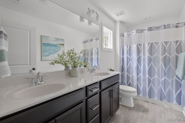 full bath featuring a sink, toilet, double vanity, and visible vents