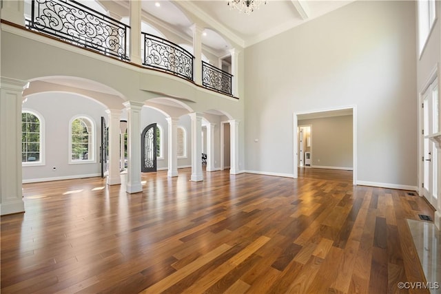 unfurnished living room with ornate columns and a towering ceiling