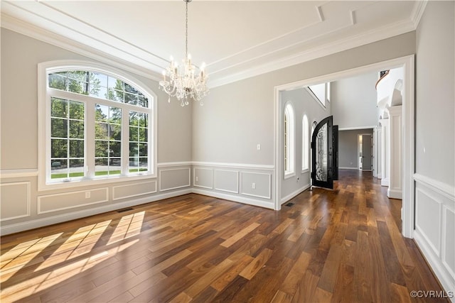 unfurnished dining area with visible vents, ornamental molding, a decorative wall, and an inviting chandelier