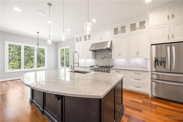 kitchen featuring stove, stainless steel fridge, recessed lighting, under cabinet range hood, and a sink