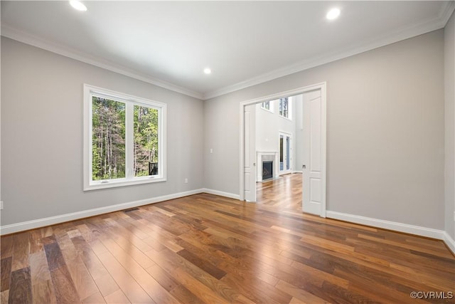 unfurnished room with baseboards, ornamental molding, a fireplace with flush hearth, and hardwood / wood-style flooring