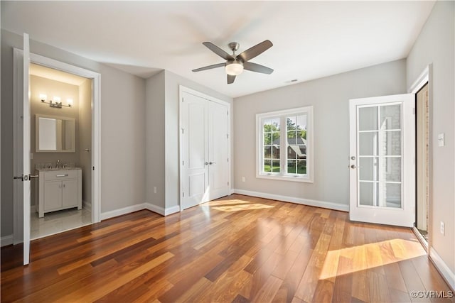 unfurnished bedroom featuring visible vents, wood finished floors, baseboards, ceiling fan, and a sink
