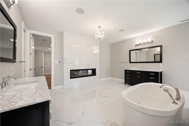 bathroom with a high end fireplace, a freestanding tub, two vanities, a sink, and marble finish floor