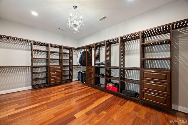 walk in closet with a notable chandelier, wood finished floors, and visible vents