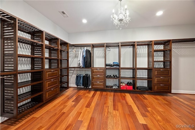 walk in closet with visible vents, wood finished floors, and a chandelier