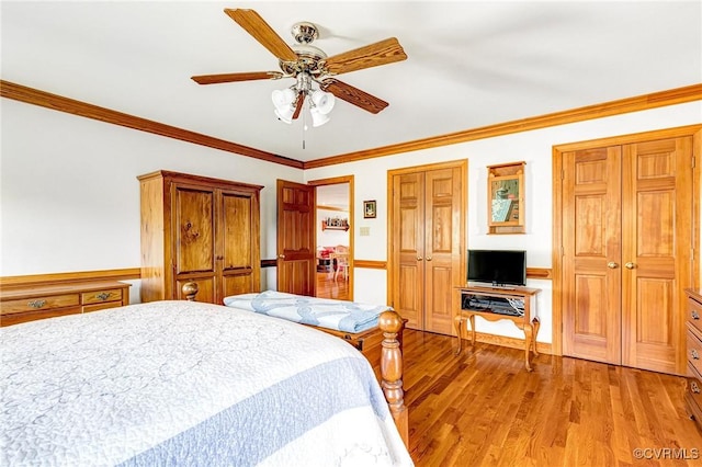 bedroom featuring light wood-style floors, ornamental molding, wainscoting, and ceiling fan