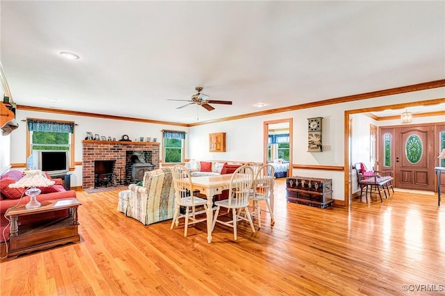 living area featuring light wood-style flooring, a brick fireplace, and a wealth of natural light