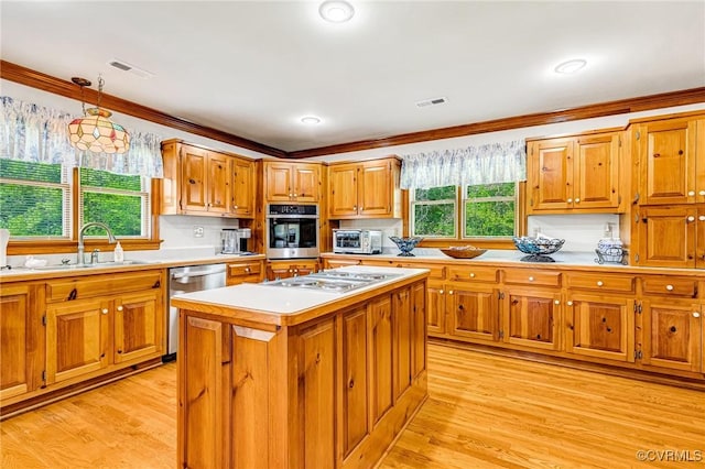 kitchen with brown cabinetry, visible vents, appliances with stainless steel finishes, a sink, and light countertops