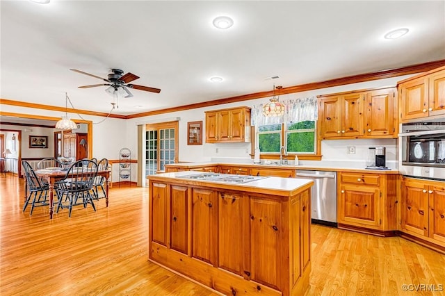 kitchen featuring stainless steel appliances, ceiling fan with notable chandelier, light wood finished floors, and a center island