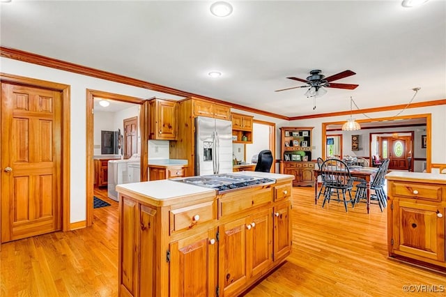 kitchen featuring stainless steel fridge with ice dispenser, light countertops, cooktop, washer / dryer, and light wood-type flooring