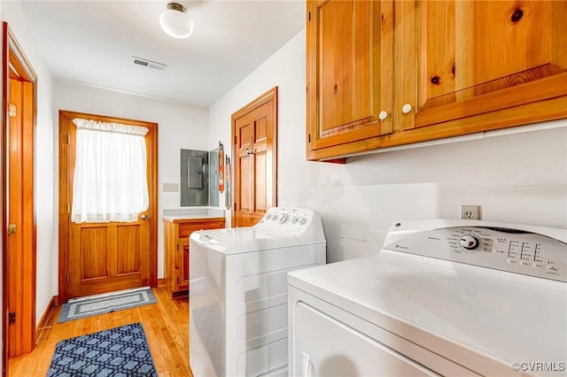 laundry room featuring cabinet space, light wood-style floors, visible vents, washing machine and dryer, and electric panel