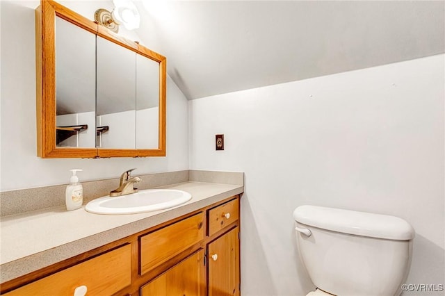 bathroom featuring vanity, lofted ceiling, and toilet