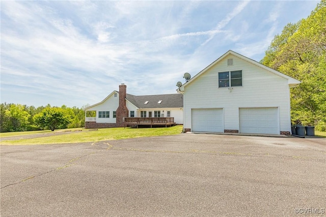 view of home's exterior featuring a lawn, aphalt driveway, a wooden deck, and a garage