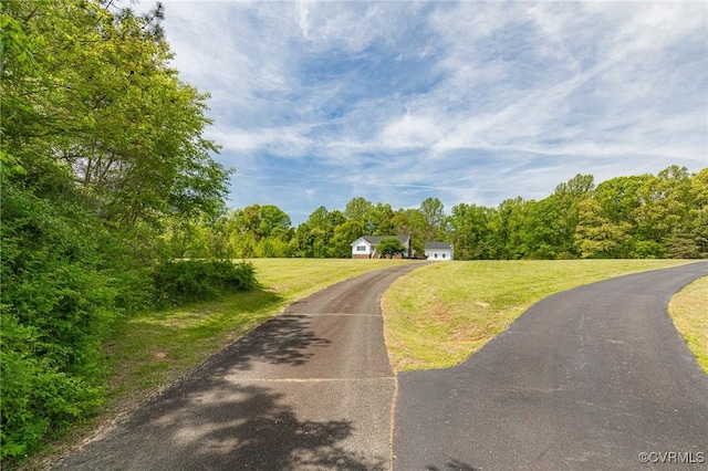 view of road with driveway and a wooded view