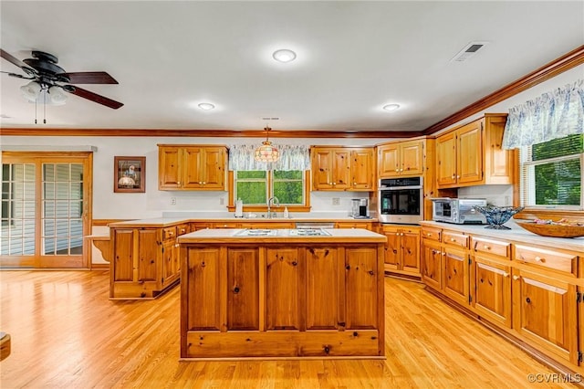 kitchen featuring crown molding, light countertops, stainless steel oven, and a kitchen island