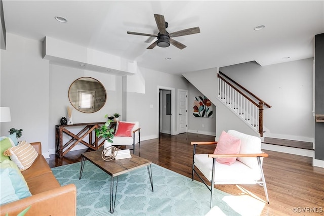living room featuring baseboards, a ceiling fan, wood finished floors, and stairway