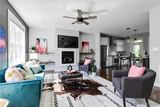 living room featuring a fireplace, a ceiling fan, recessed lighting, and dark wood-type flooring