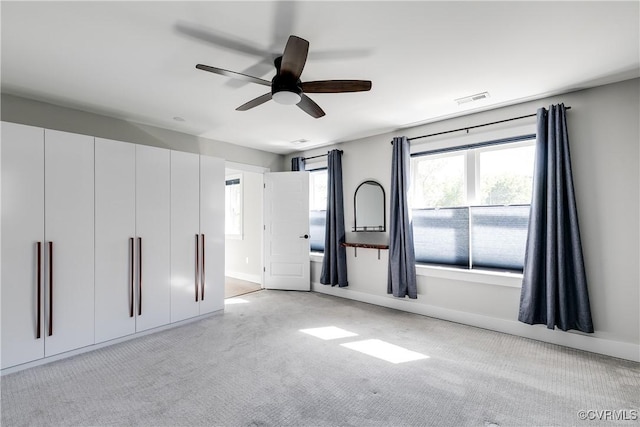 unfurnished bedroom featuring a ceiling fan, baseboards, light colored carpet, and visible vents