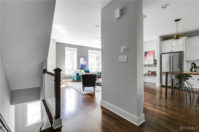 corridor featuring baseboards, an upstairs landing, and dark wood-style floors