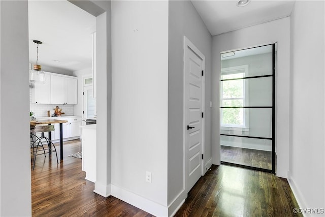 corridor featuring baseboards and dark wood-type flooring