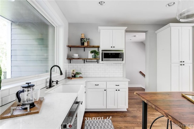 kitchen featuring backsplash, open shelves, a sink, white cabinets, and stainless steel microwave