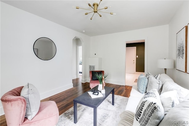 living area featuring arched walkways, baseboards, wood finished floors, and a chandelier