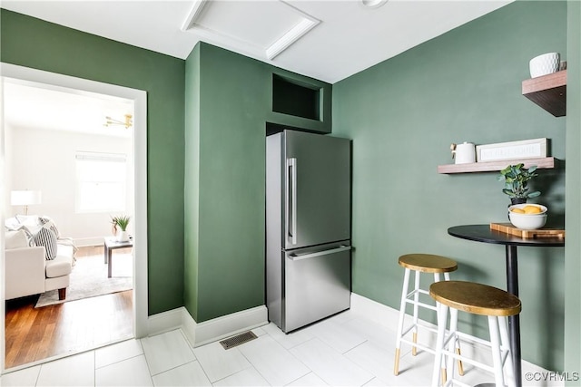 kitchen featuring visible vents, freestanding refrigerator, and baseboards