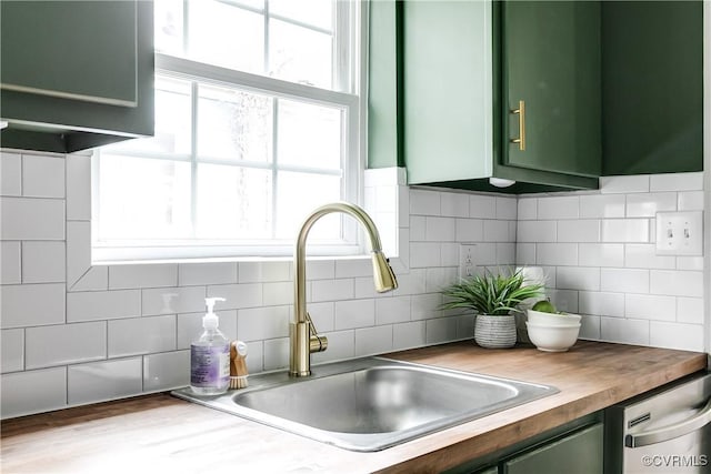 room details with a sink, wooden counters, tasteful backsplash, stainless steel dishwasher, and green cabinets