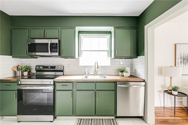 kitchen with a sink, green cabinets, and stainless steel appliances