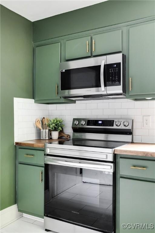kitchen featuring appliances with stainless steel finishes, green cabinetry, decorative backsplash, and wood counters