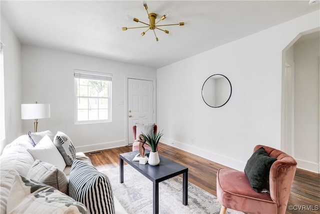 living area with arched walkways, baseboards, and wood finished floors