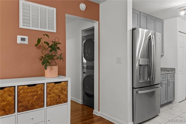 1712 Halifax Ave, Richmond, VA 23224 - kitchen with visible vents, gray cabinetry, baseboards, stacked washing maching and dryer, and stainless steel fridge