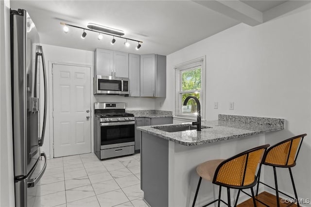 1712 Halifax Ave, Richmond, VA 23224 - kitchen featuring gray cabinets, a kitchen bar, appliances with stainless steel finishes, a sink, and a peninsula