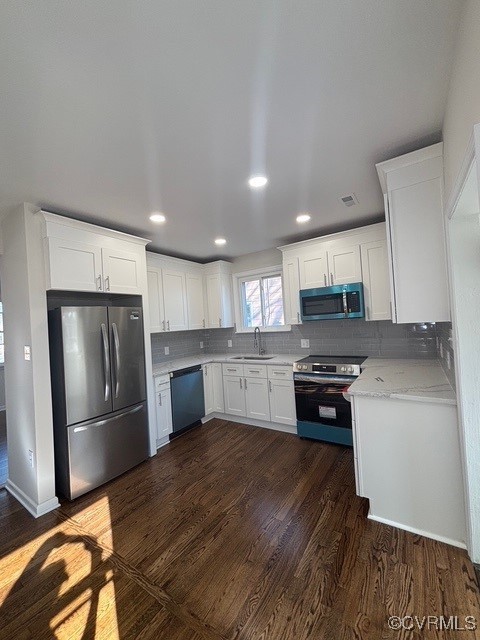 kitchen with white cabinetry, backsplash, dark wood-style floors, and stainless steel appliances