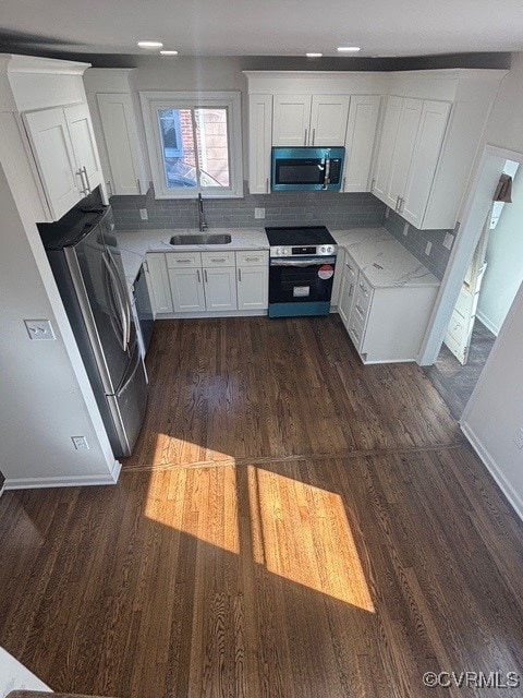 kitchen with white cabinets, a sink, stainless steel appliances, decorative backsplash, and dark wood-type flooring