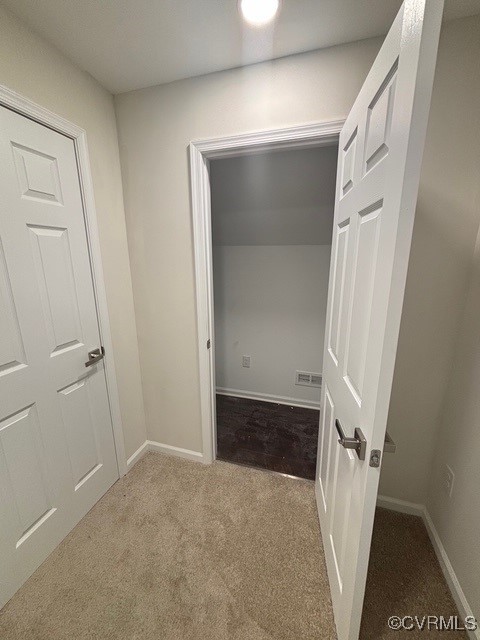 corridor featuring baseboards and carpet
