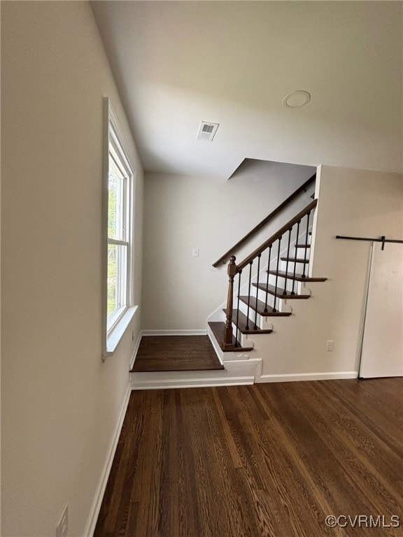 stairway with baseboards, wood finished floors, and visible vents
