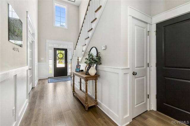 foyer with a wainscoted wall, wood finished floors, and a wealth of natural light