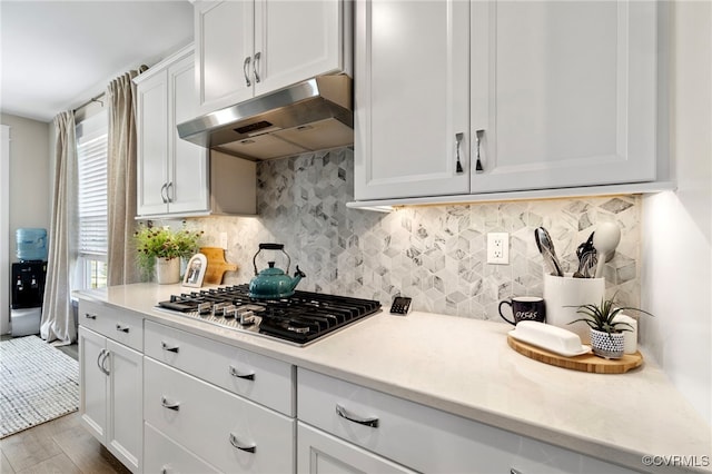 kitchen featuring under cabinet range hood, light countertops, stainless steel gas stovetop, and wood finished floors