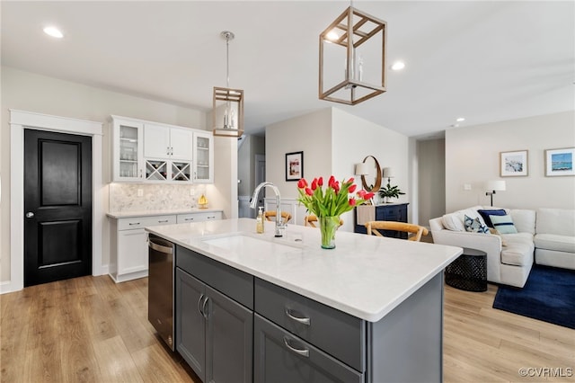 kitchen featuring white cabinetry, a sink, light countertops, gray cabinetry, and light wood-style flooring