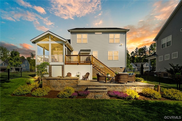 back of property at dusk with stairs, a wooden deck, a fenced backyard, an outdoor living space, and a lawn