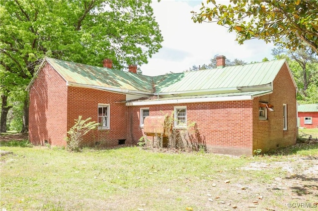 back of property with brick siding, crawl space, a lawn, and a chimney