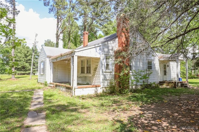 view of side of home featuring a lawn and a chimney