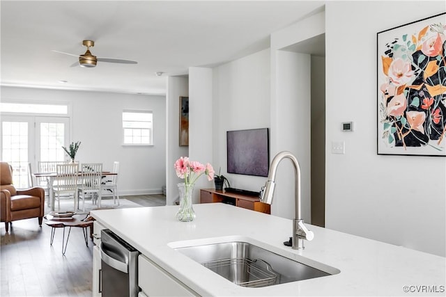kitchen with a sink, light wood-style floors, light countertops, open floor plan, and stainless steel dishwasher